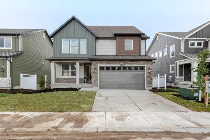 Contemporary two-story residence featuring a covered front porch, a two-car garage, stone and board-and-batten siding, a concrete driveway, and established landscaping