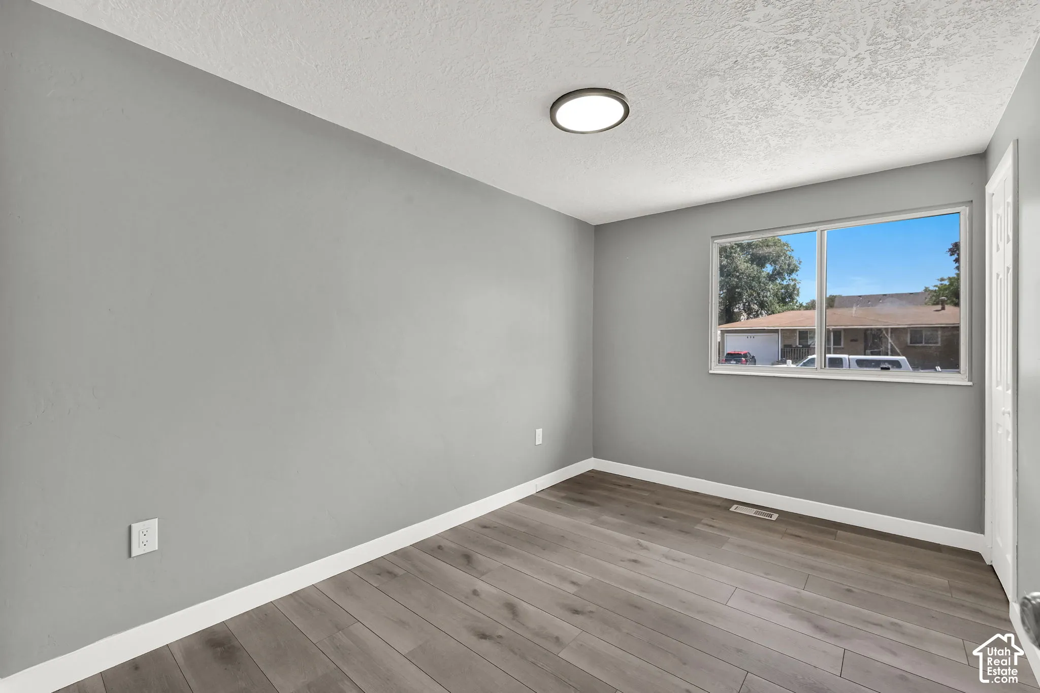 Interior room featuring wood-finish flooring, light gray walls, and white baseboards