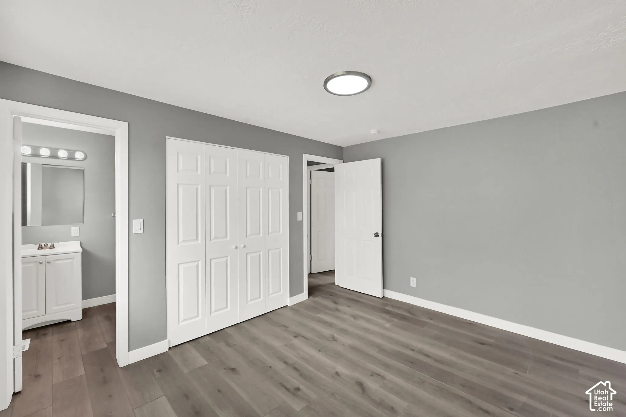 Primary bedroom featuring light gray walls, wood-finish flooring, and white baseboards