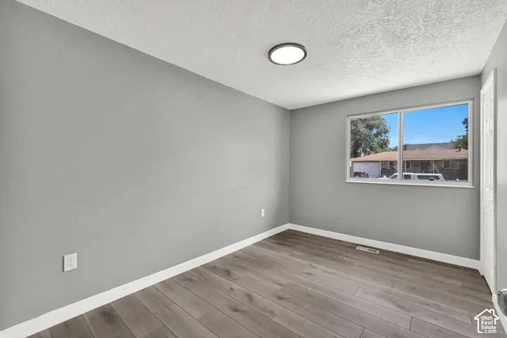 Interior room featuring wood-finish flooring, light gray walls, and white baseboards