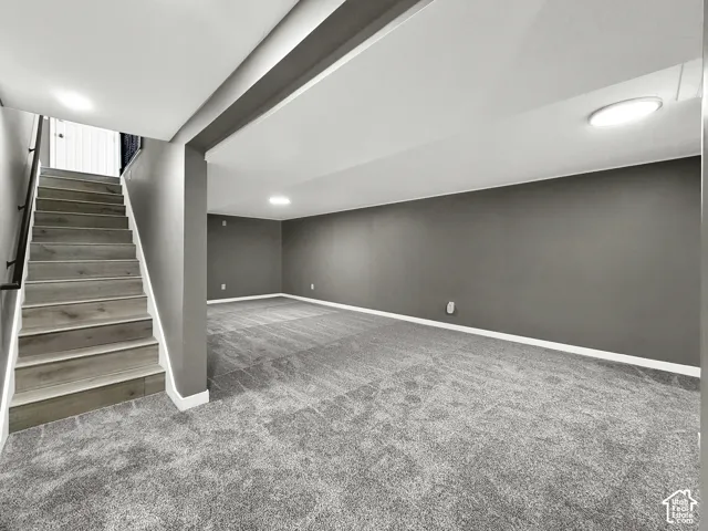 Finished basement area featuring plush gray carpeting, neutral wall color, and recessed ceiling lighting