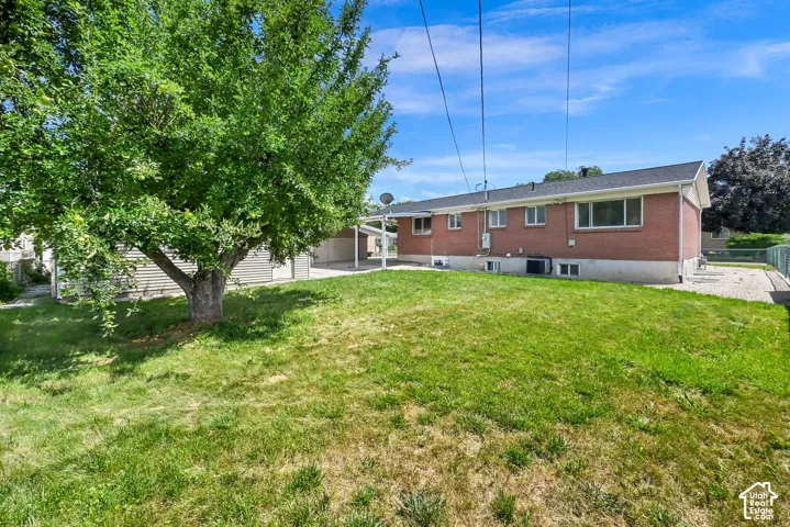 Expansive grassy yard area with a mature shade tree and a red brick exterior.