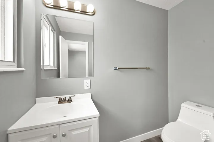 White corner vanity with an integrated sink, brushed brass faucet, and a rectangular mirror.