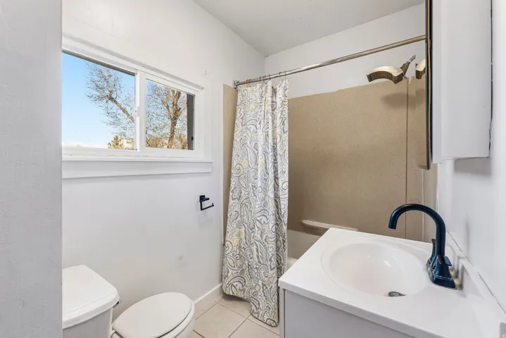 Bathroom featuring vanity, shower / tub combo, and light tile patterned floors