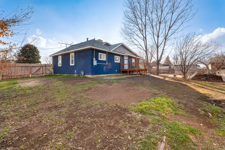Back of property with a fenced backyard, stucco siding, a deck, and a gate