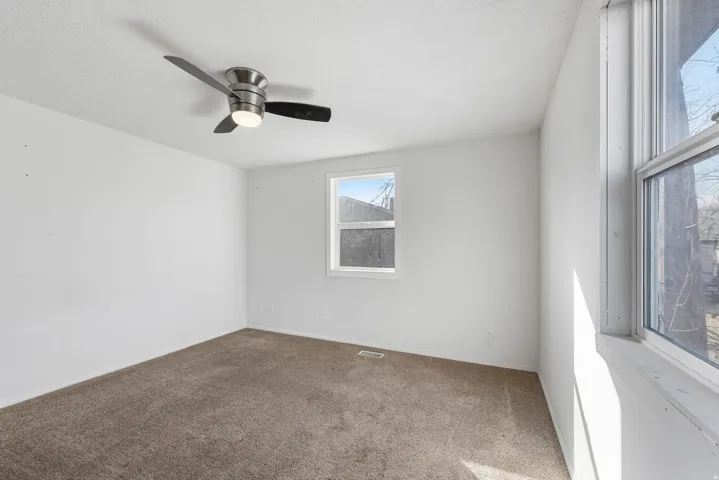 Carpeted empty room featuring ceiling fan and baseboards