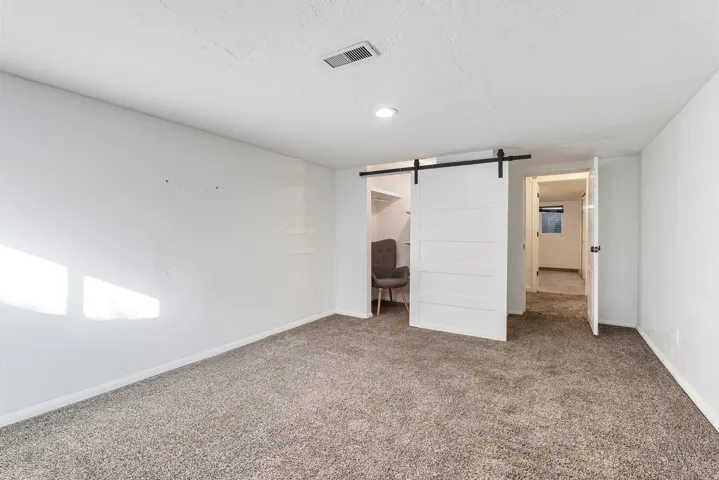 Unfurnished bedroom with a barn door, carpet floors, a spacious closet, and a textured ceiling