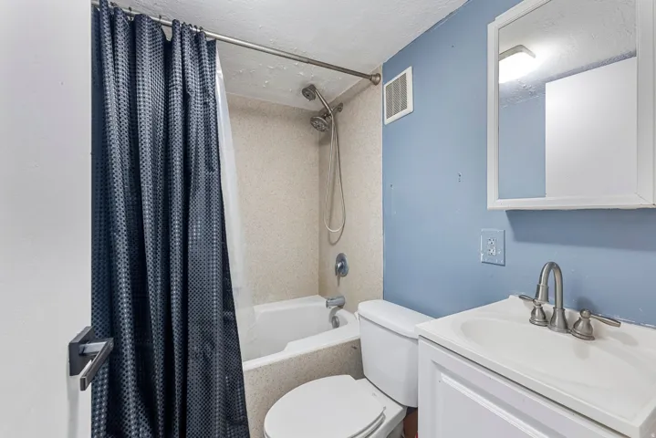 Bathroom featuring a textured ceiling, shower / tub combo, and vanity