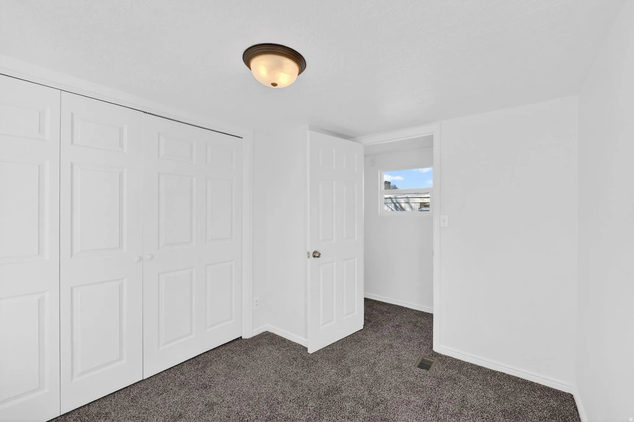 Unfurnished bedroom featuring dark carpet and a closet