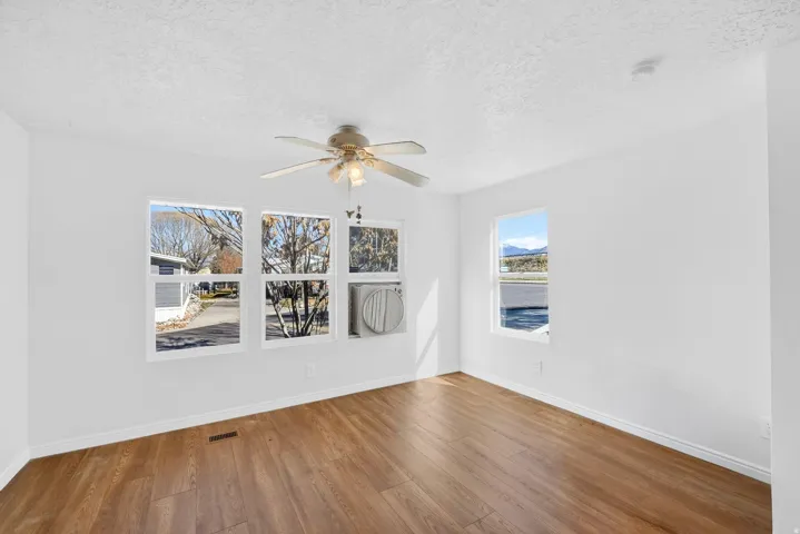 Empty room featuring ceiling fan, wood finished floors, and a textured ceiling