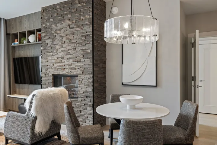 Dining room with wood finished floors, a stone fireplace, and suspended lighting