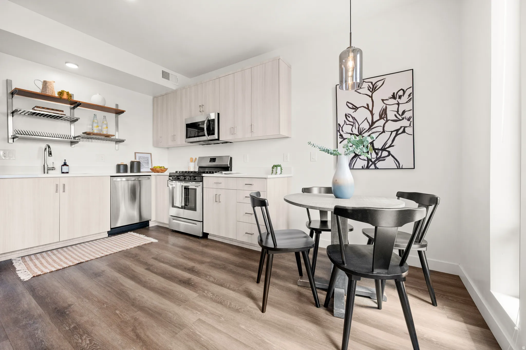 Kitchen featuring stainless steel appliances, open shelves, dark wood-style floors, light countertops, and light wood finish cabinets