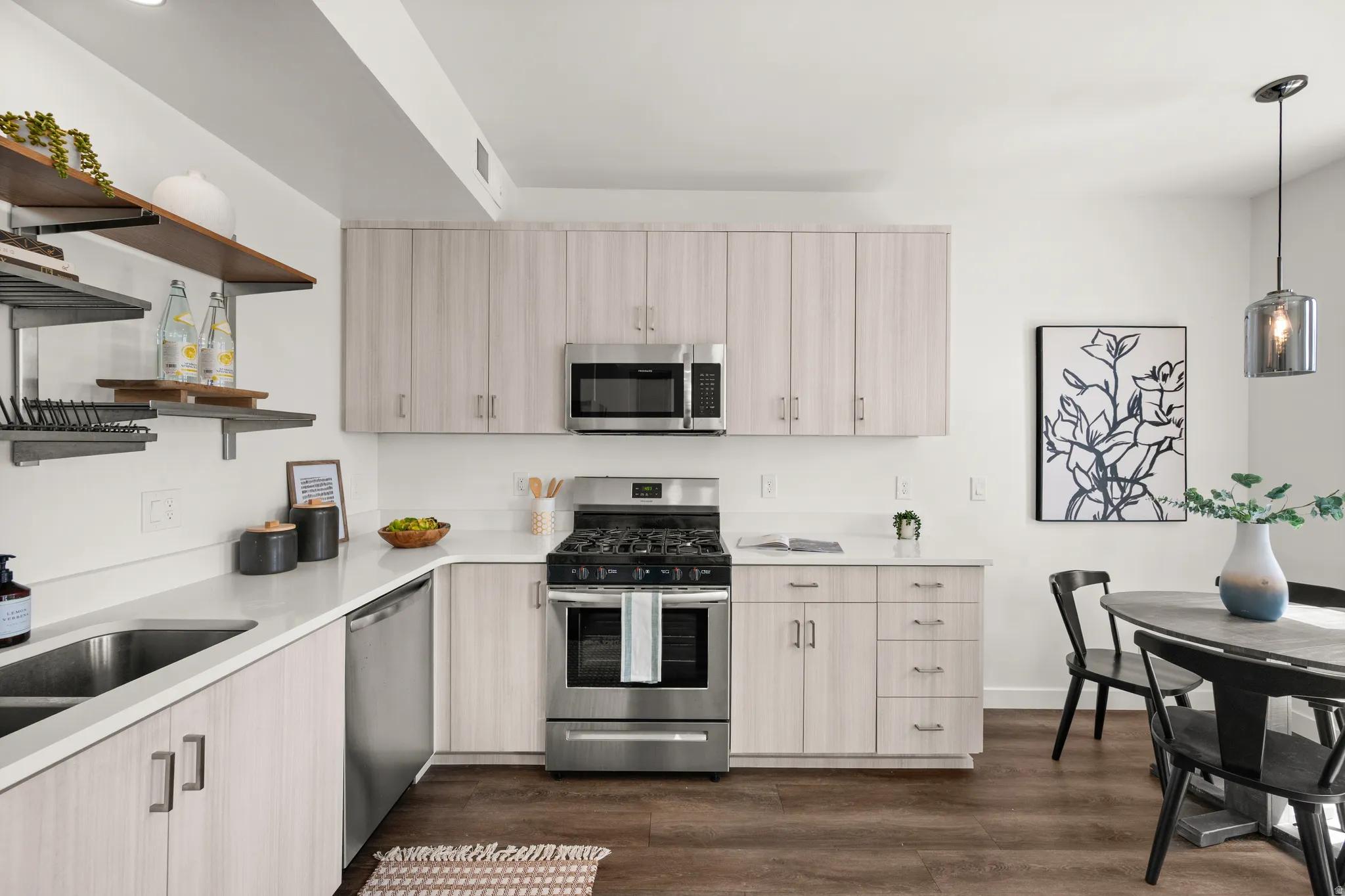 Kitchen featuring open shelves, stainless steel appliances, decorative light fixtures, dark wood finished floors, and light wood finish cabinets