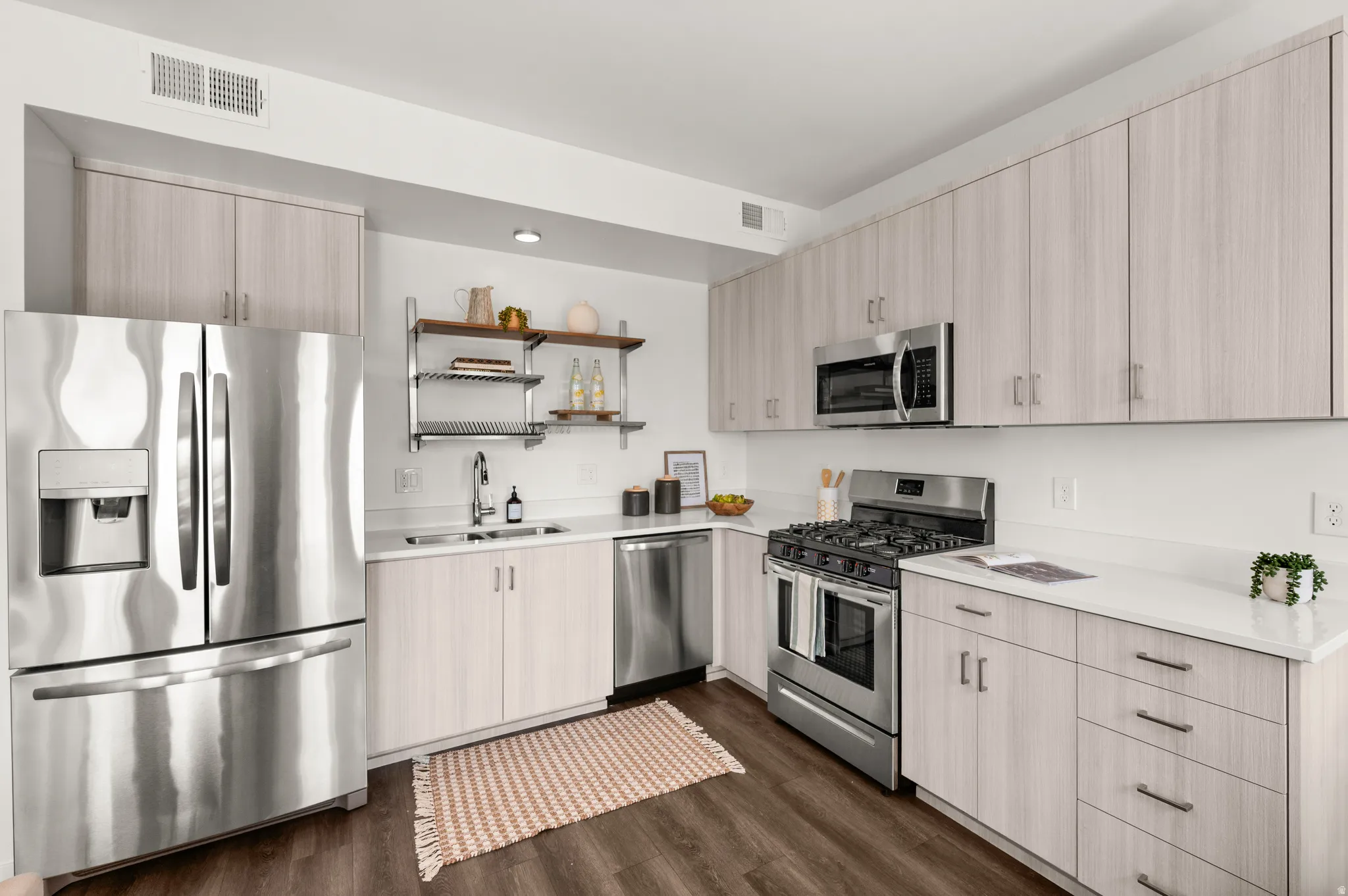 Kitchen featuring stainless steel appliances, light wood finish cabinets, open shelves, and dark wood-style floors