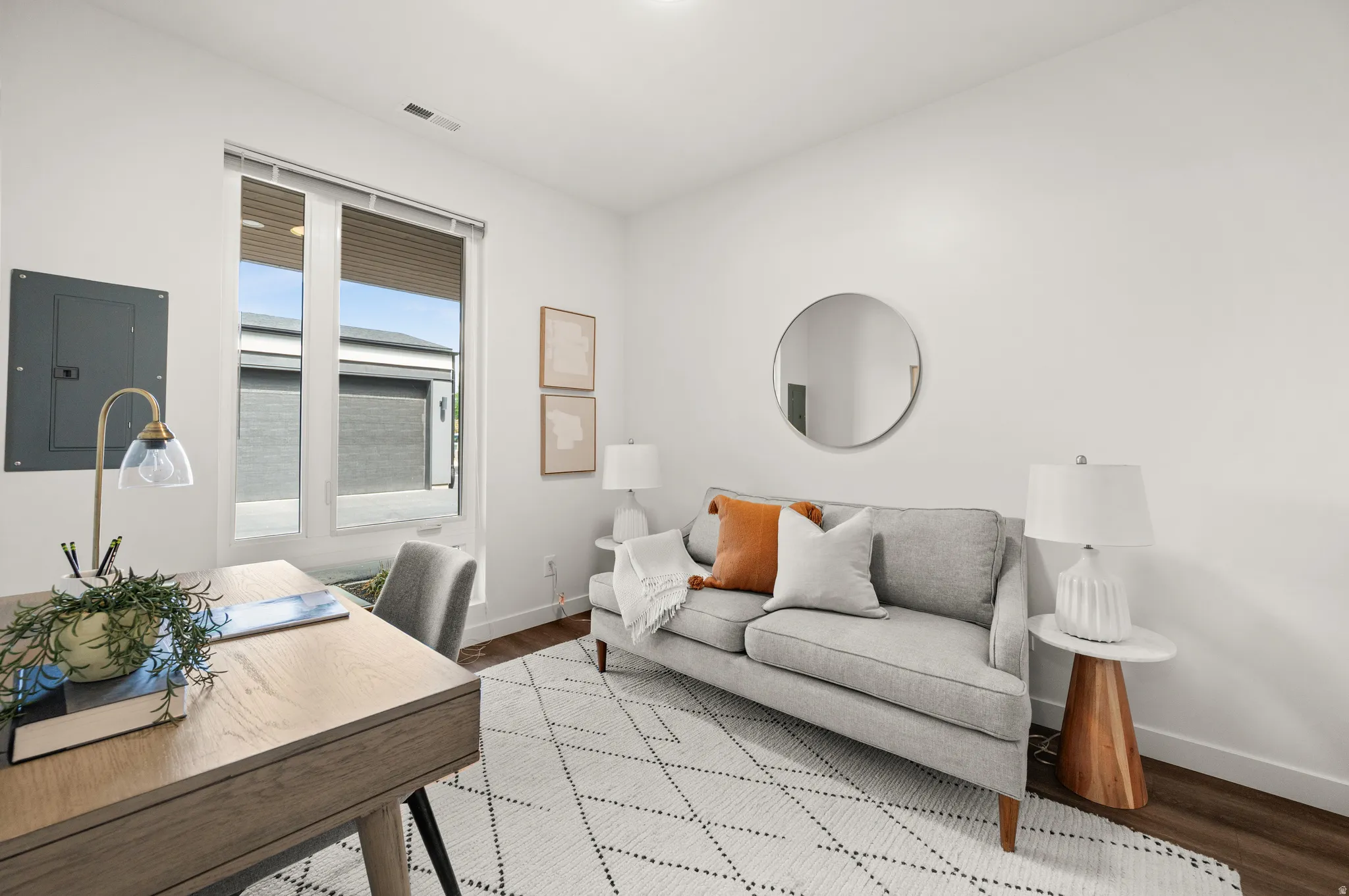 Home office featuring electric panel and wood finished floors