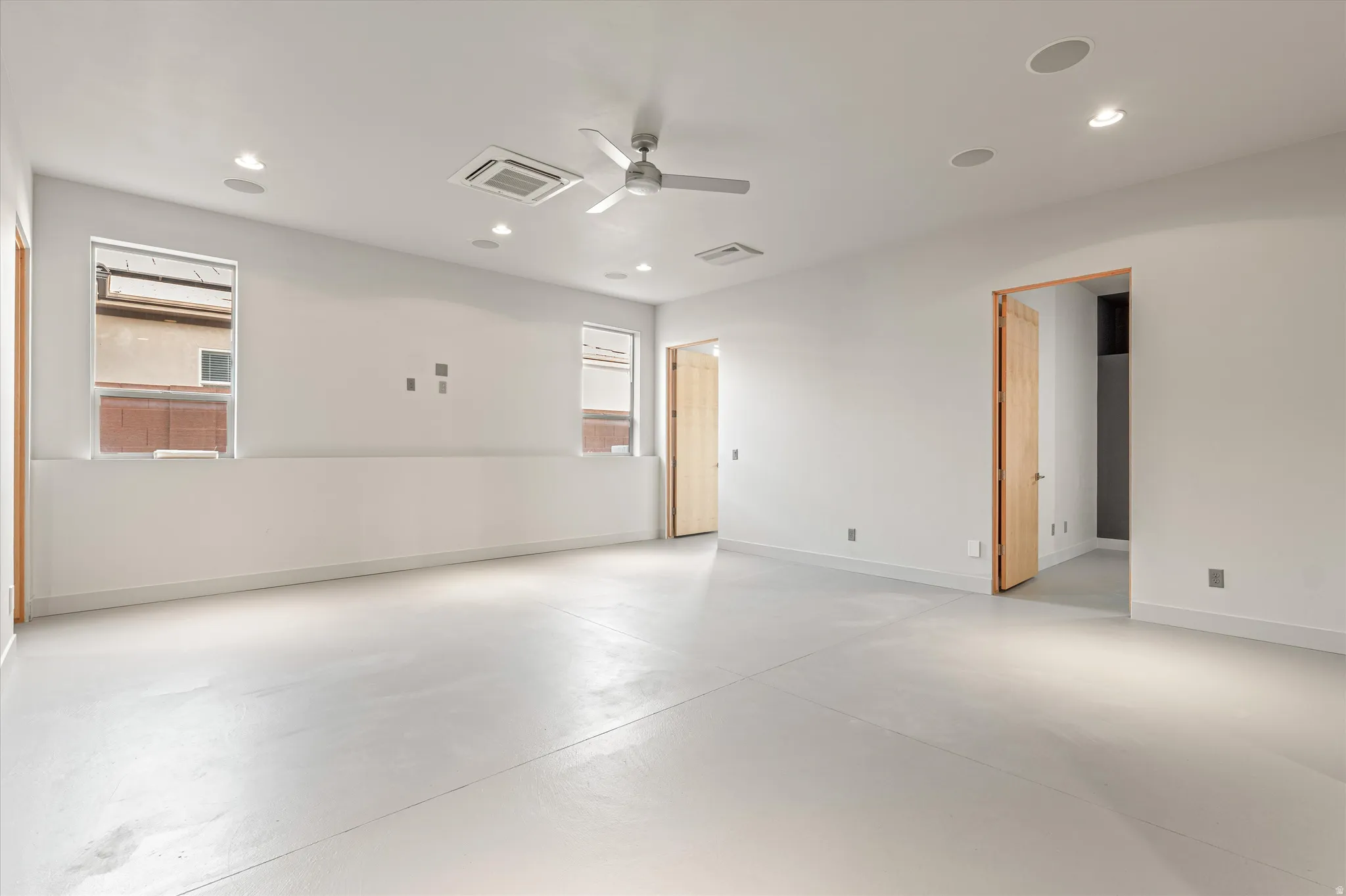 Empty room with concrete floors, ceiling fan, healthy amount of natural light, cooling unit, and recessed lighting