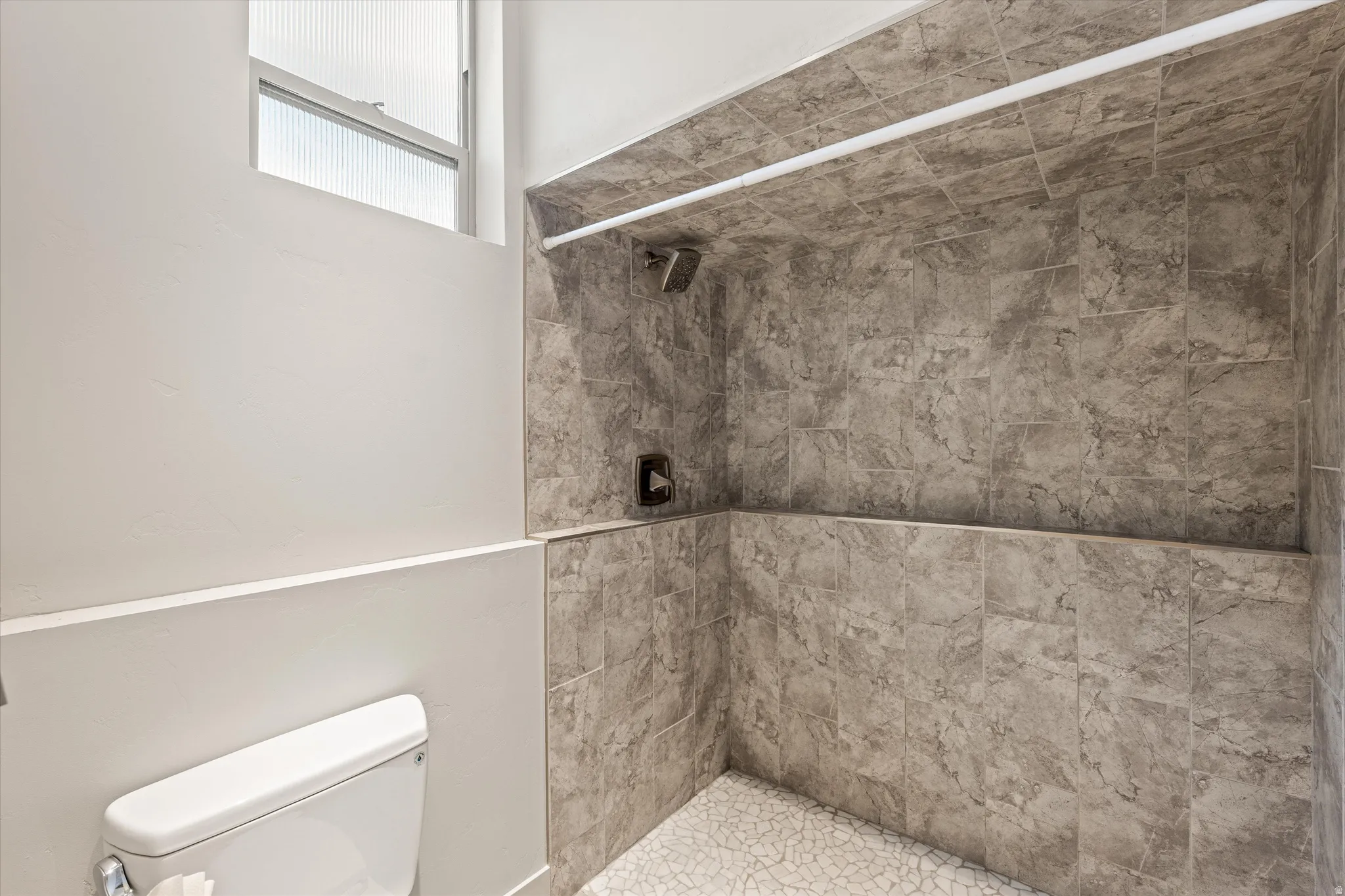 Full bathroom featuring a tile shower and toilet