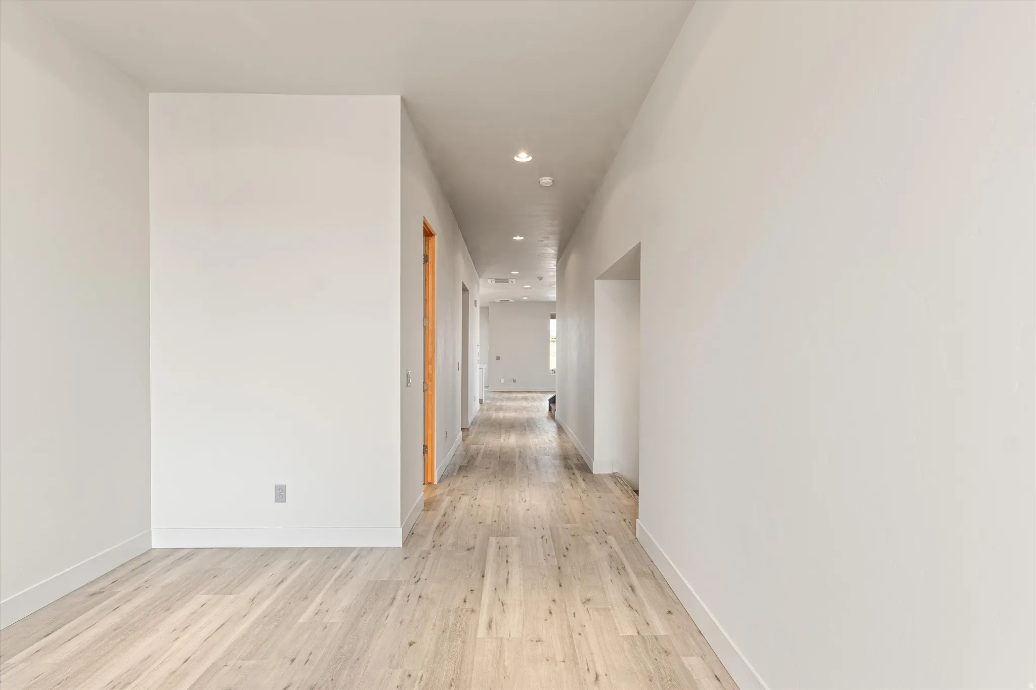 Corridor featuring light wood-type flooring and recessed lighting