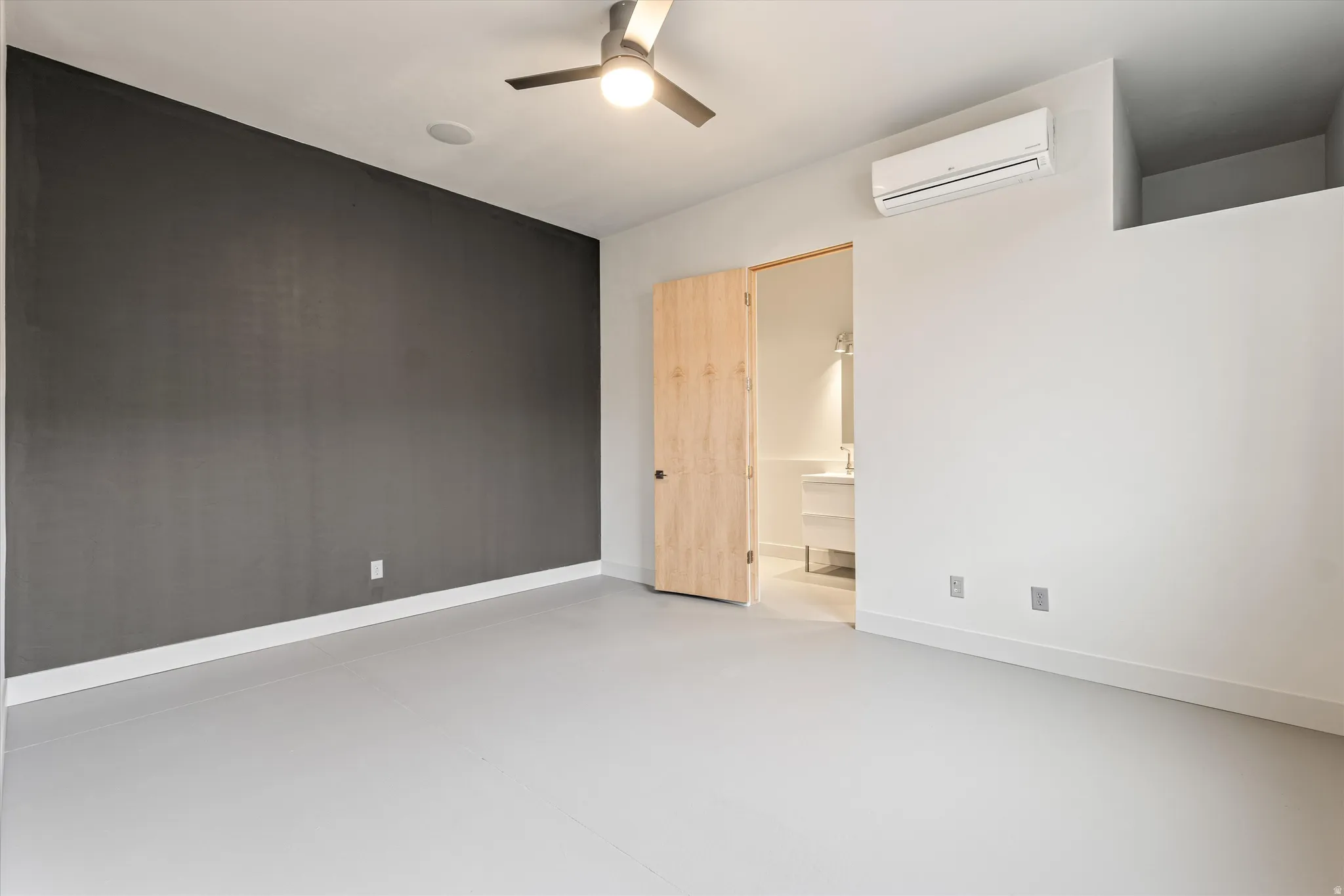 Unfurnished bedroom featuring finished concrete floors, a ceiling fan, and ensuite bathroom