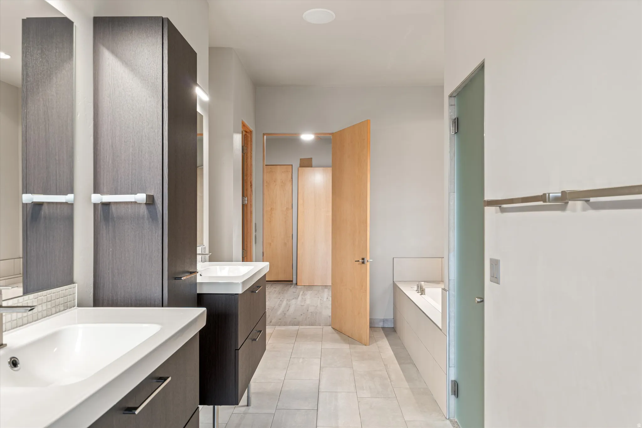 Full bathroom with a garden tub, two vanities, and light tile patterned floors
