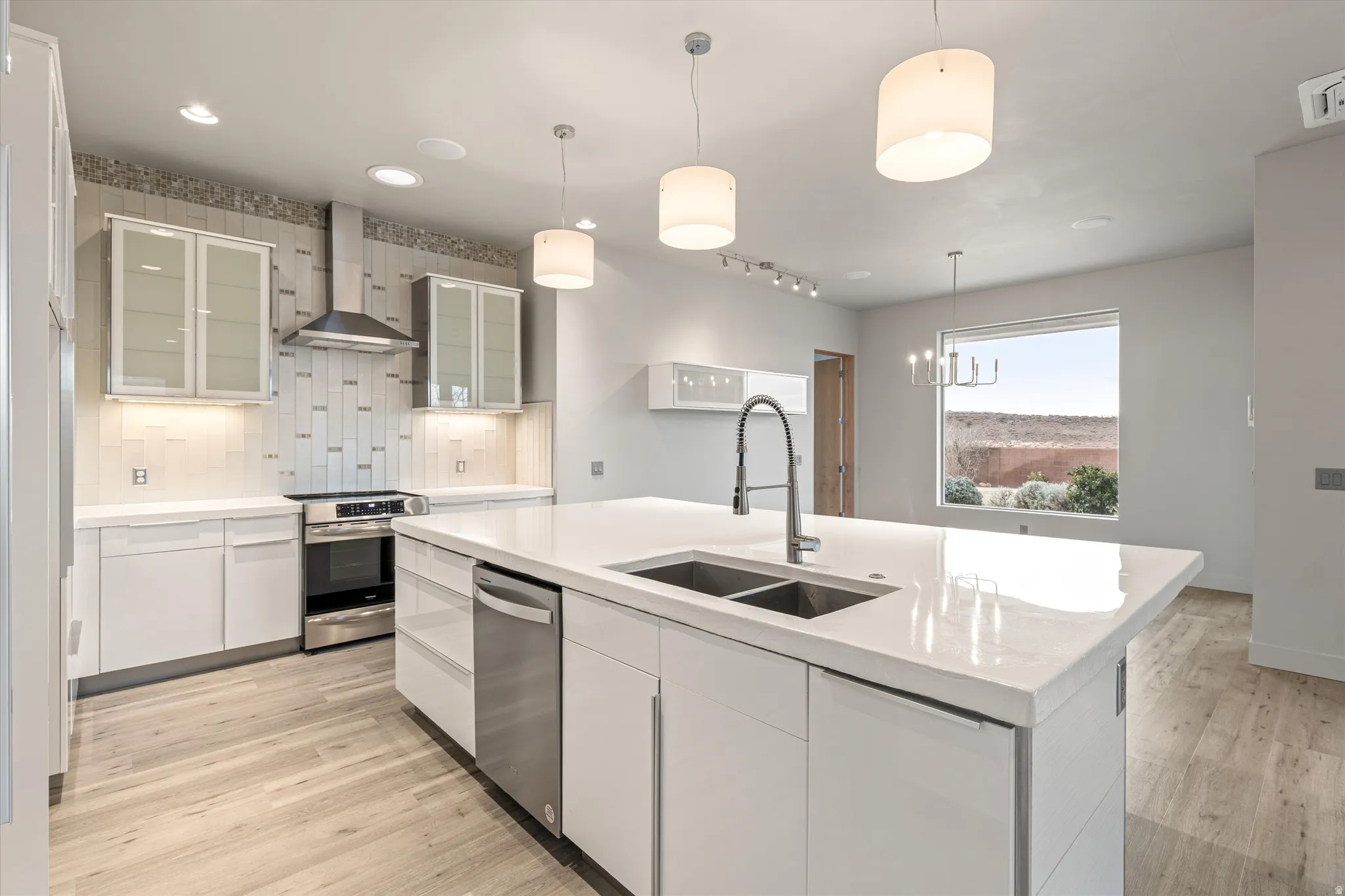 Kitchen featuring glass fronted cabinets, tasteful backsplash, a center island with sink, white cabinets, and light wood-type flooring