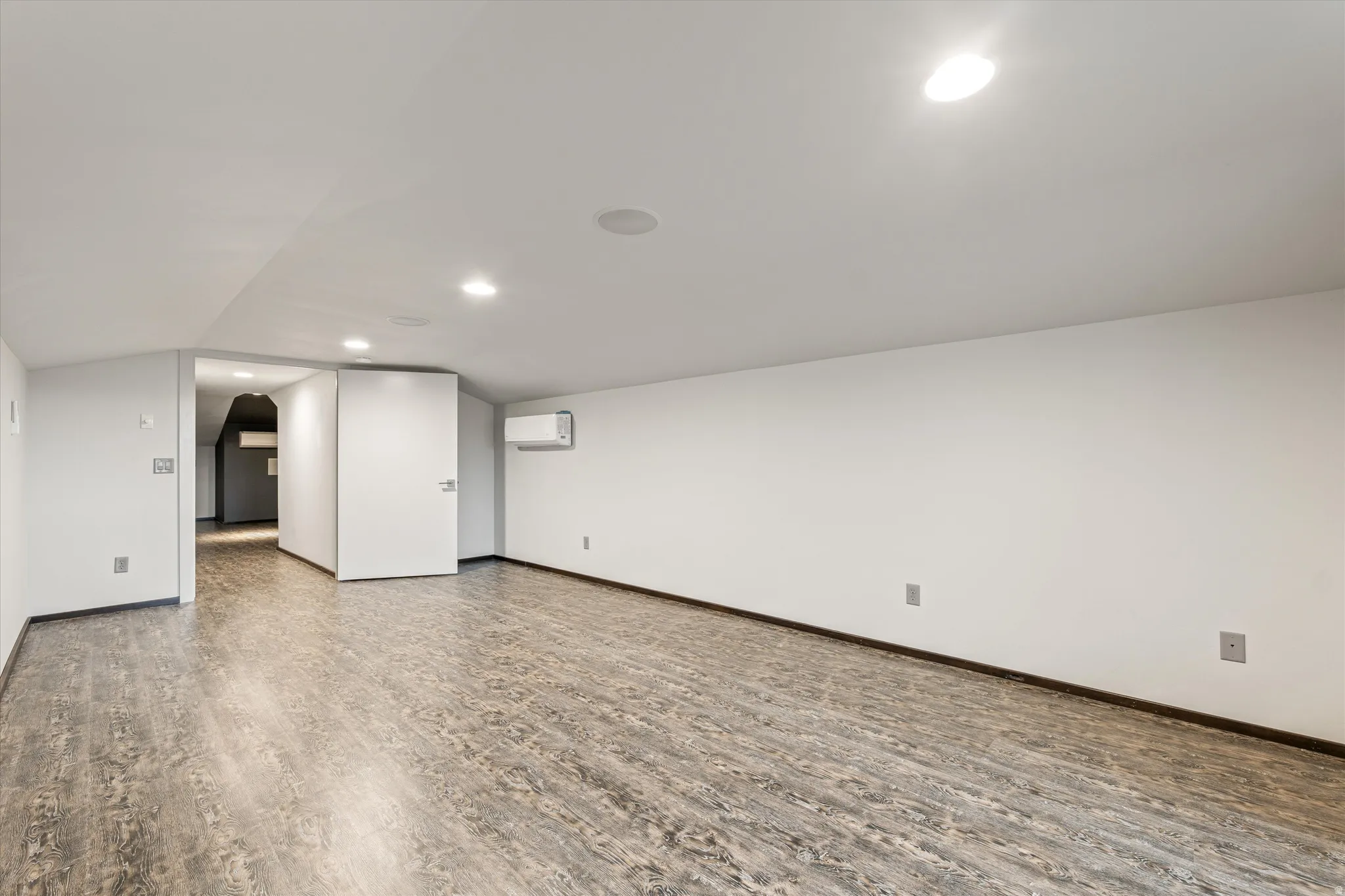 Basement featuring wood finished floors, arched walkways, and recessed lighting
