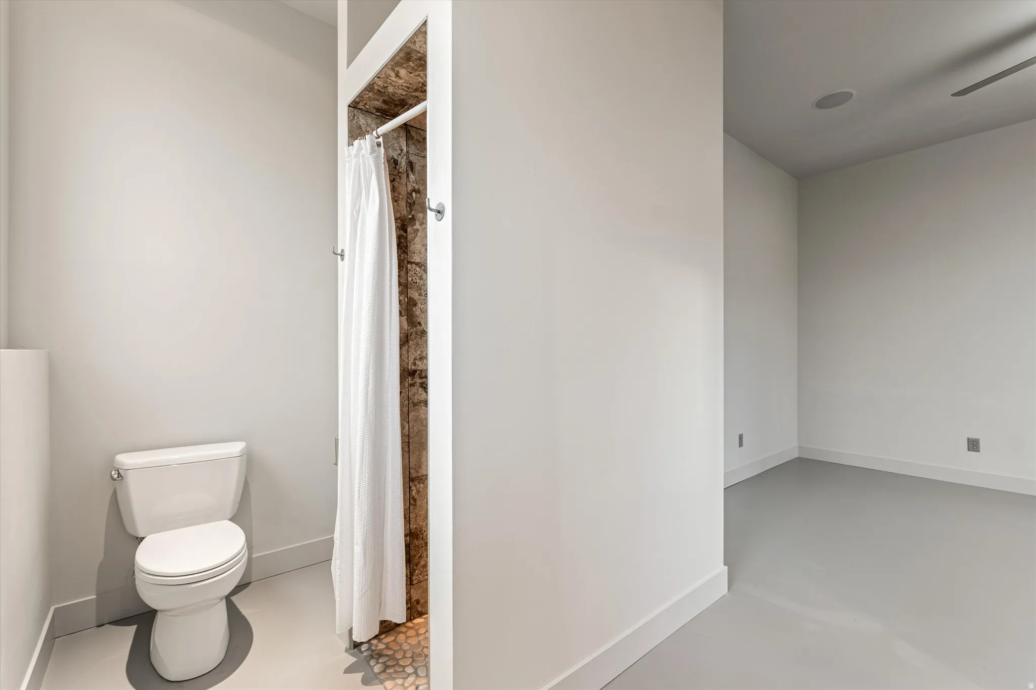 Full bathroom featuring a shower with curtain, finished concrete flooring, and a ceiling fan