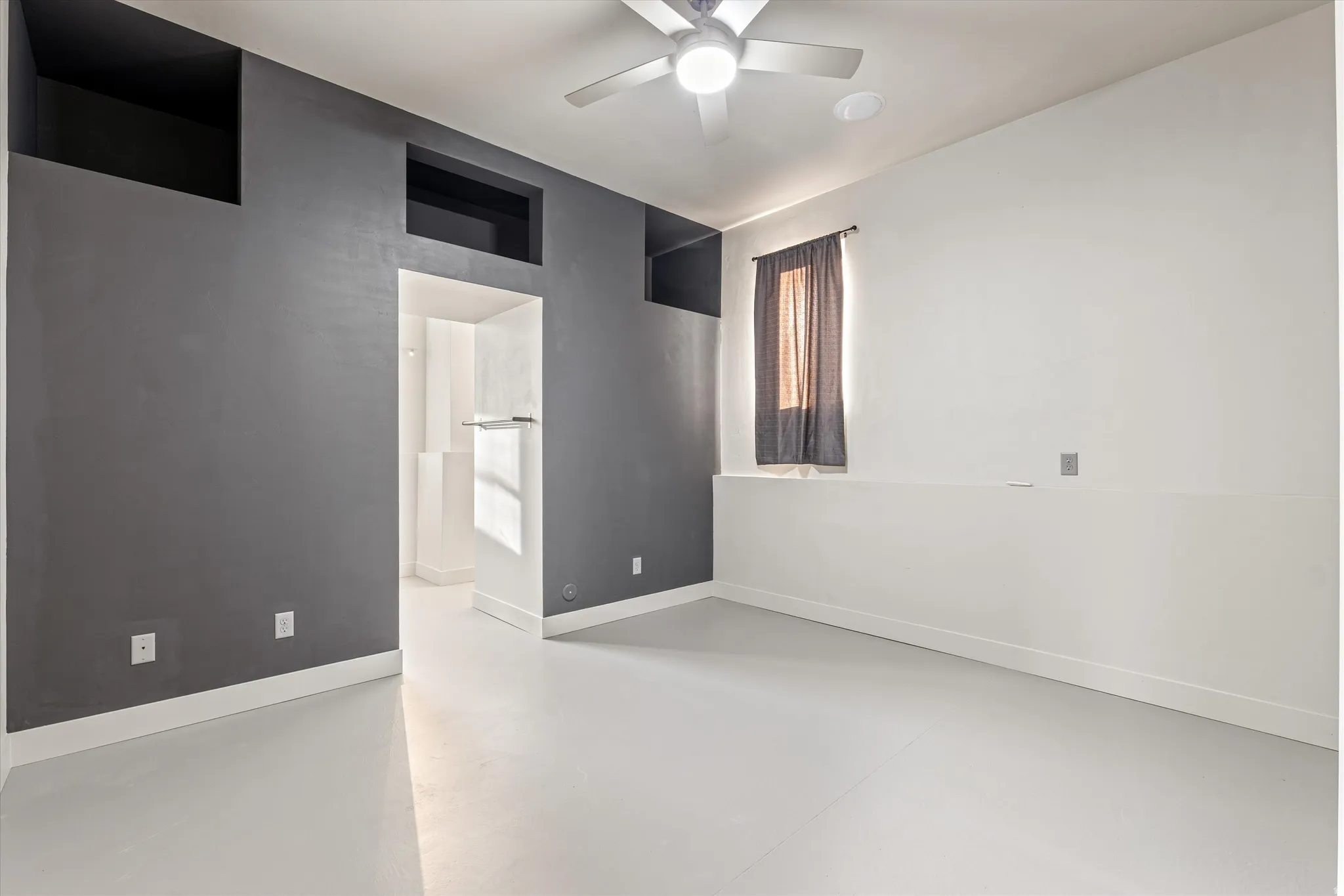 Unfurnished room with finished concrete floors and ceiling fan
