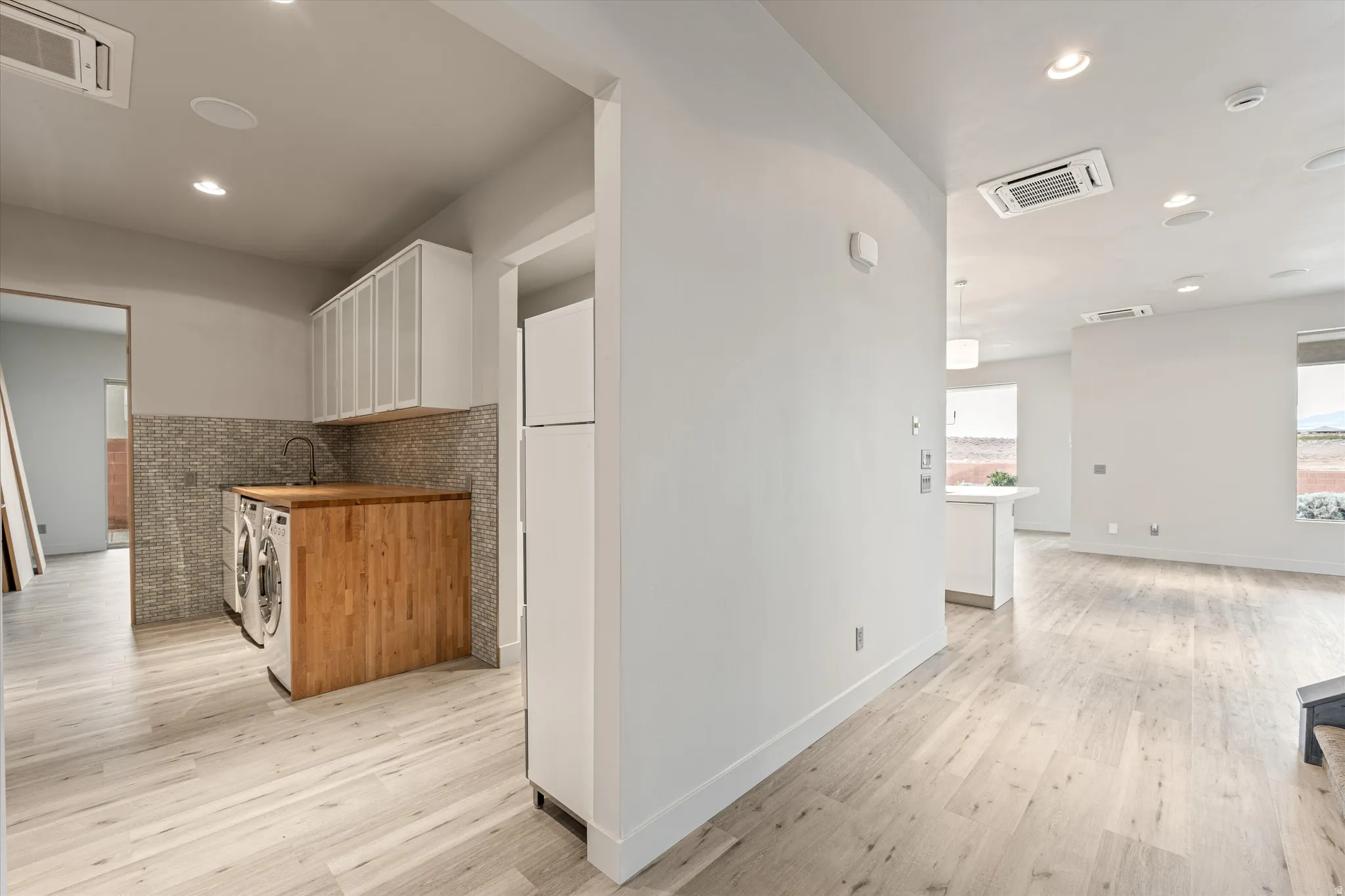 Kitchen featuring cooling unit, light wood-style flooring, recessed lighting, two tone cabinetry, and wooden counters