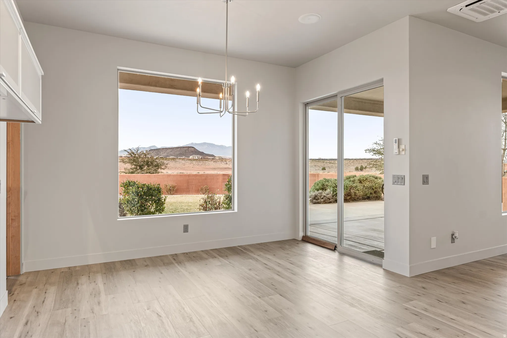 Unfurnished dining area featuring a mountain view, hanging lights, plenty of natural light, and light wood finished floors