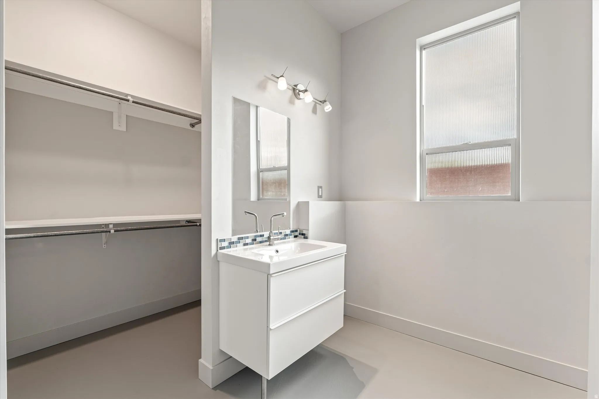 Bathroom featuring vanity, finished concrete flooring, and a spacious closet