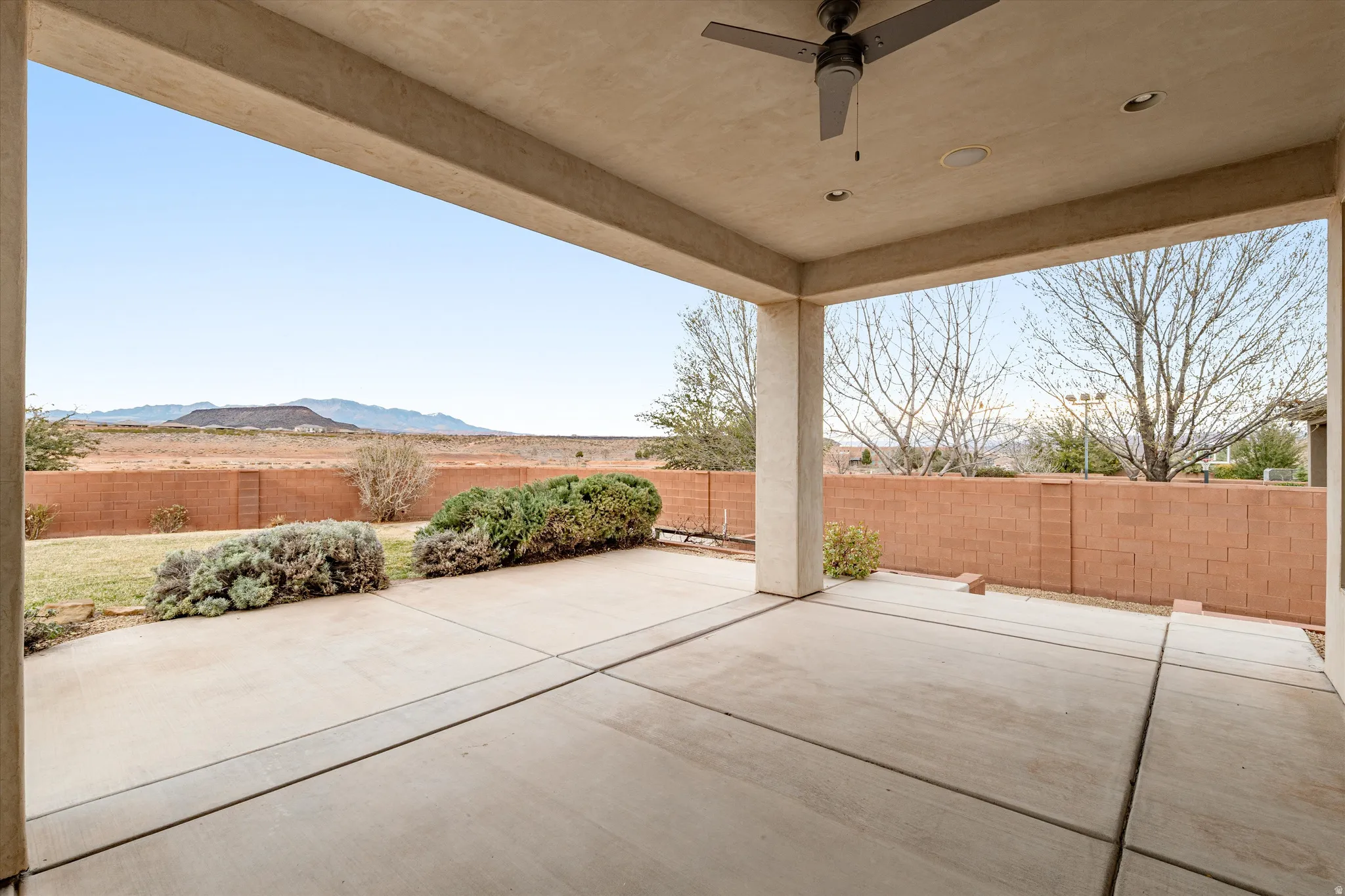 Fenced backyard with ceiling fan and a patio area