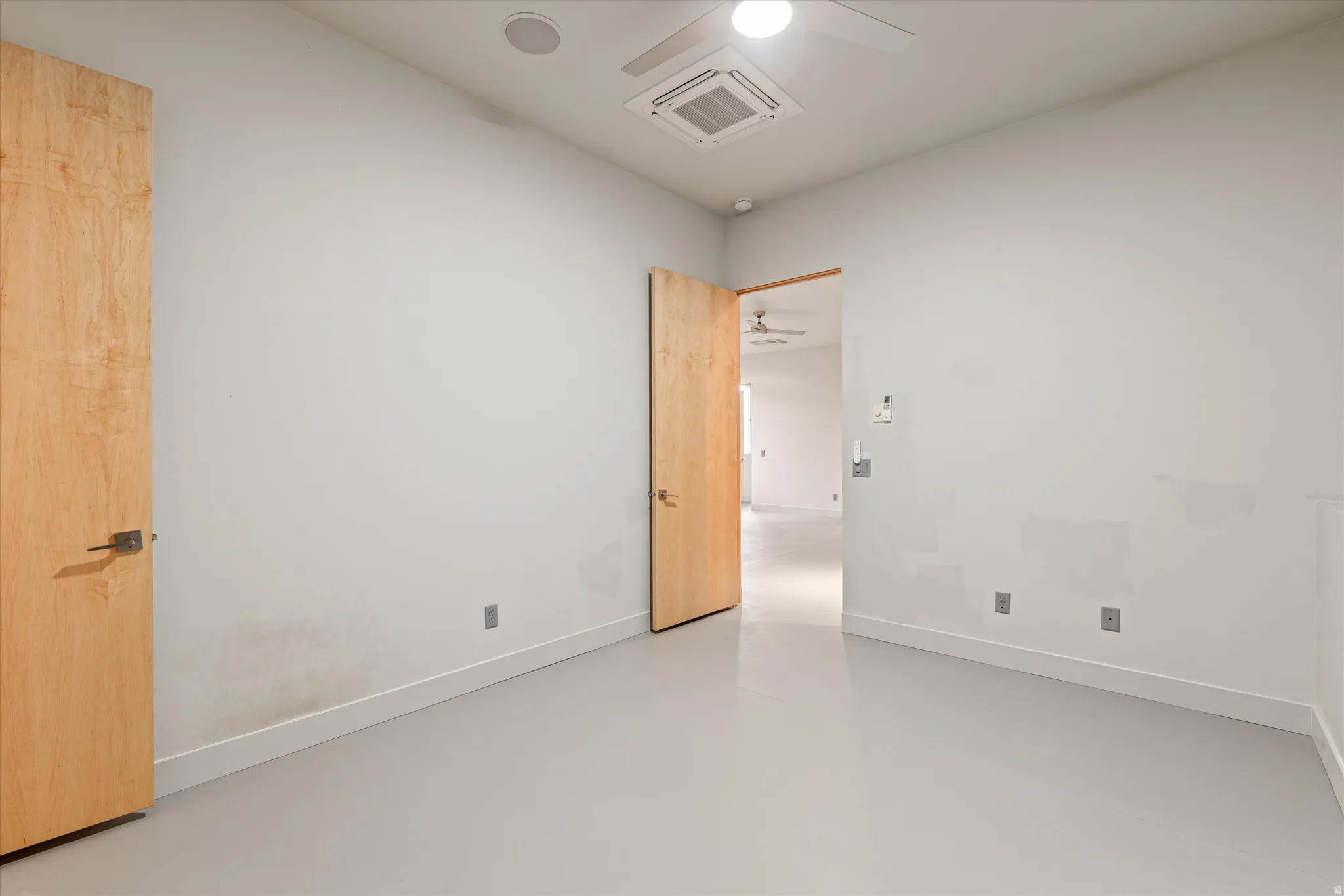 Spare room featuring concrete flooring, cooling unit, and ceiling fan
