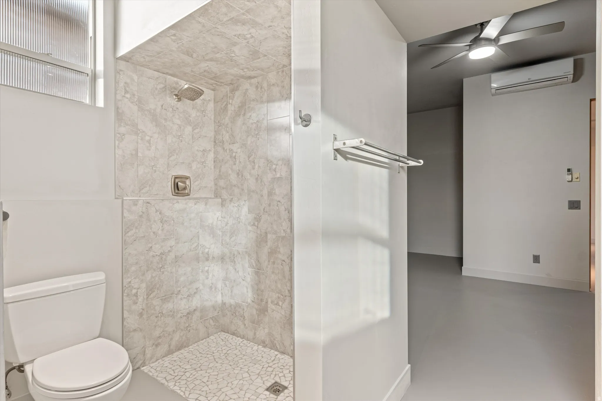 Full bath with a stall shower, ceiling fan, and finished concrete flooring