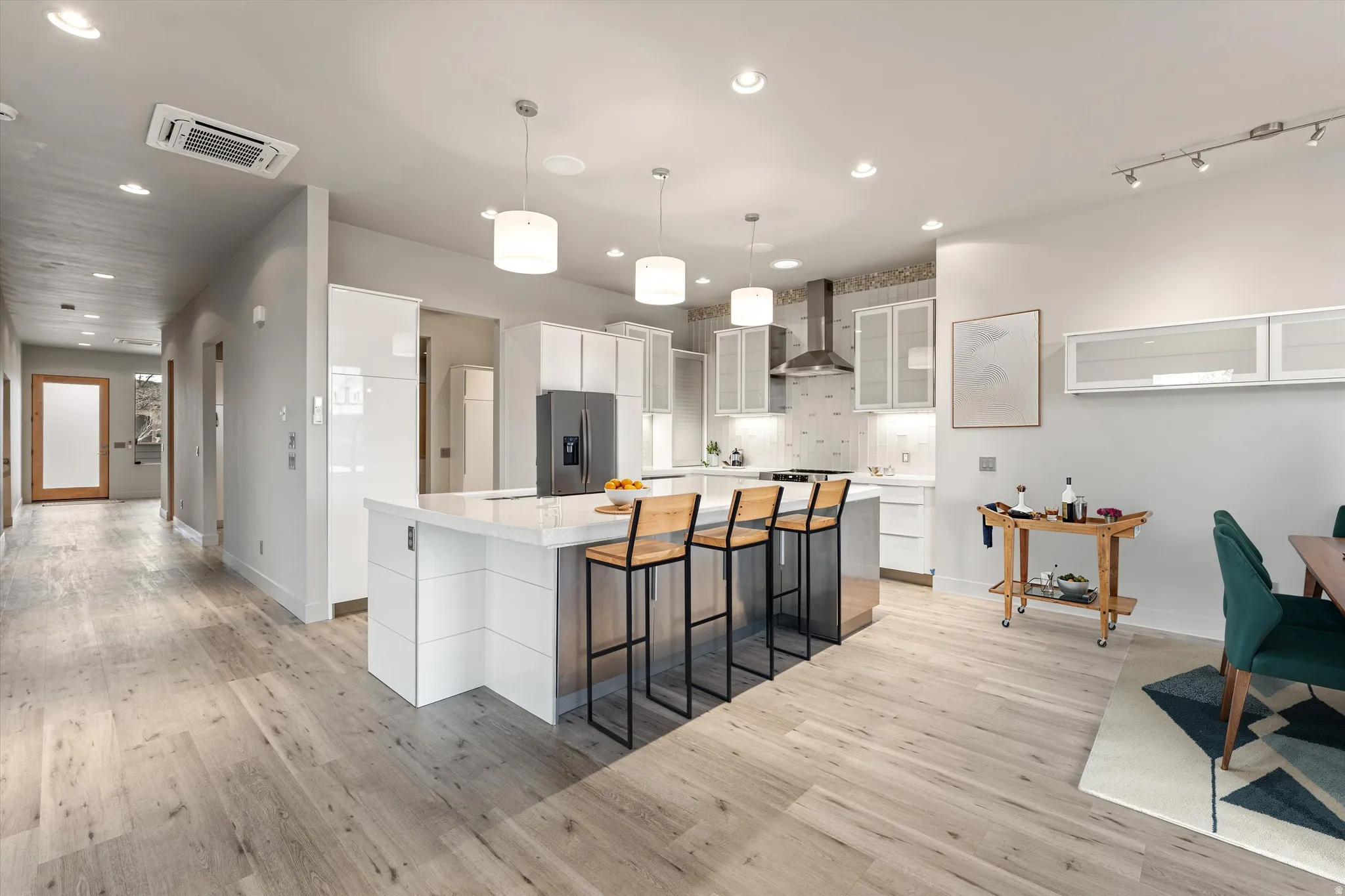 Kitchen featuring white cabinets, a kitchen bar, hanging light fixtures, light wood-type flooring, and a large island