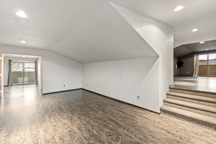 Additional living space with lofted ceiling, recessed lighting, and wood finished floors