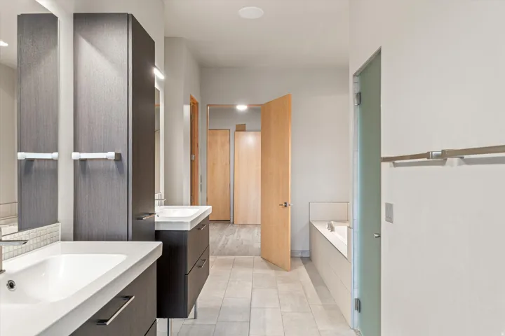 Full bathroom with a garden tub, two vanities, and light tile patterned floors