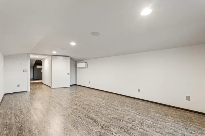 Basement featuring wood finished floors, arched walkways, and recessed lighting