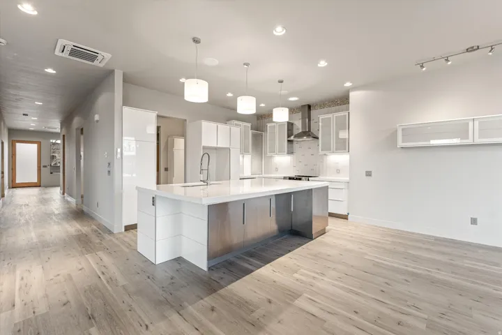 Kitchen with modern cabinets, a spacious island, glass insert cabinets, pendant lighting, and light wood finished floors
