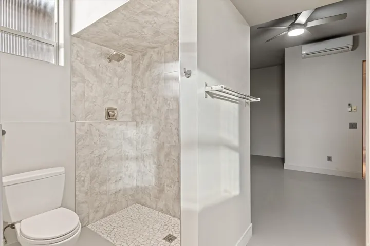 Full bath with a stall shower, ceiling fan, and finished concrete flooring