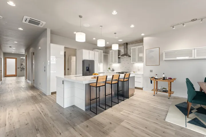 Kitchen featuring white cabinets, a kitchen bar, hanging light fixtures, light wood-type flooring, and a large island