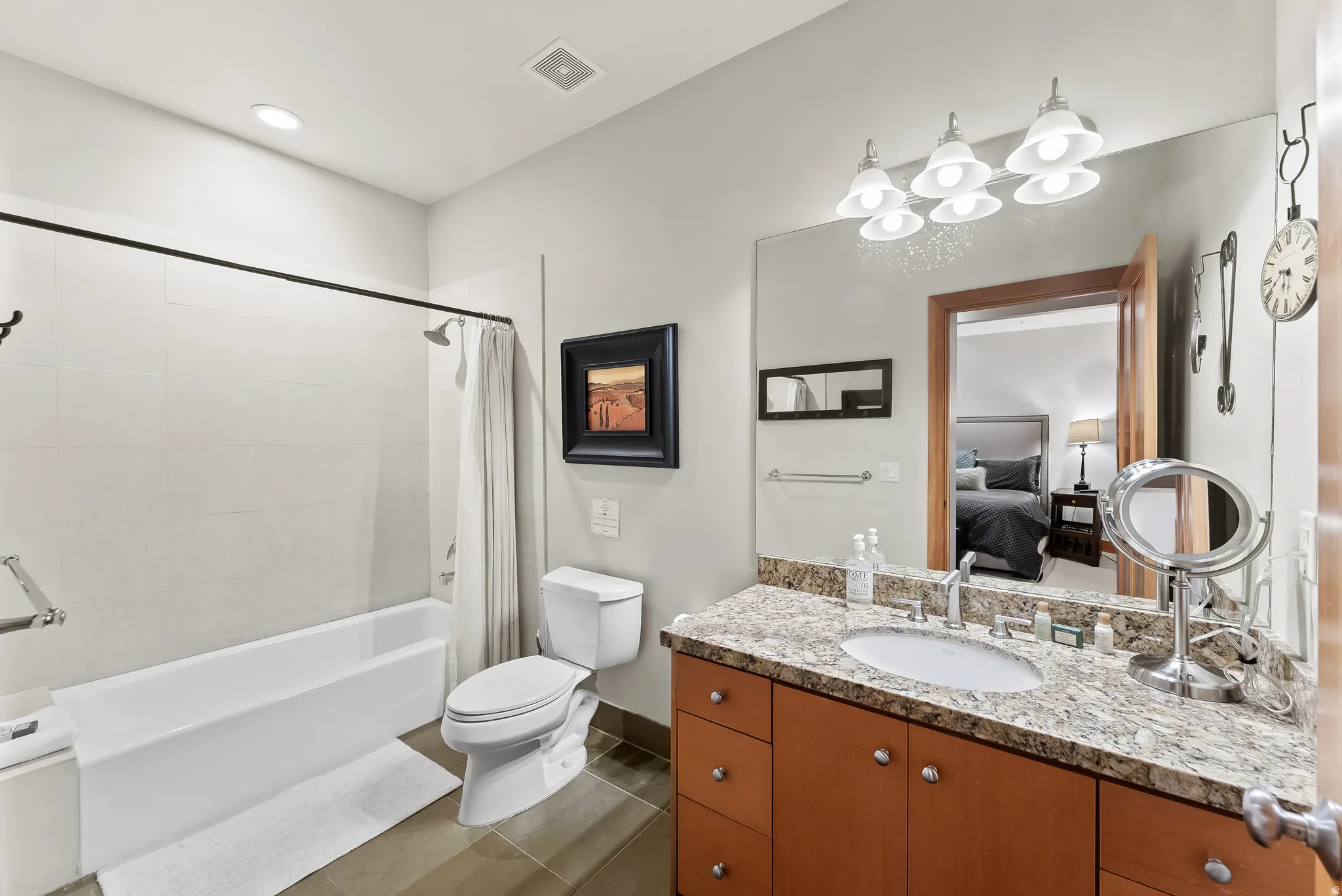 Ensuite bathroom with vanity, shower / tub combo, and dark tile patterned floors