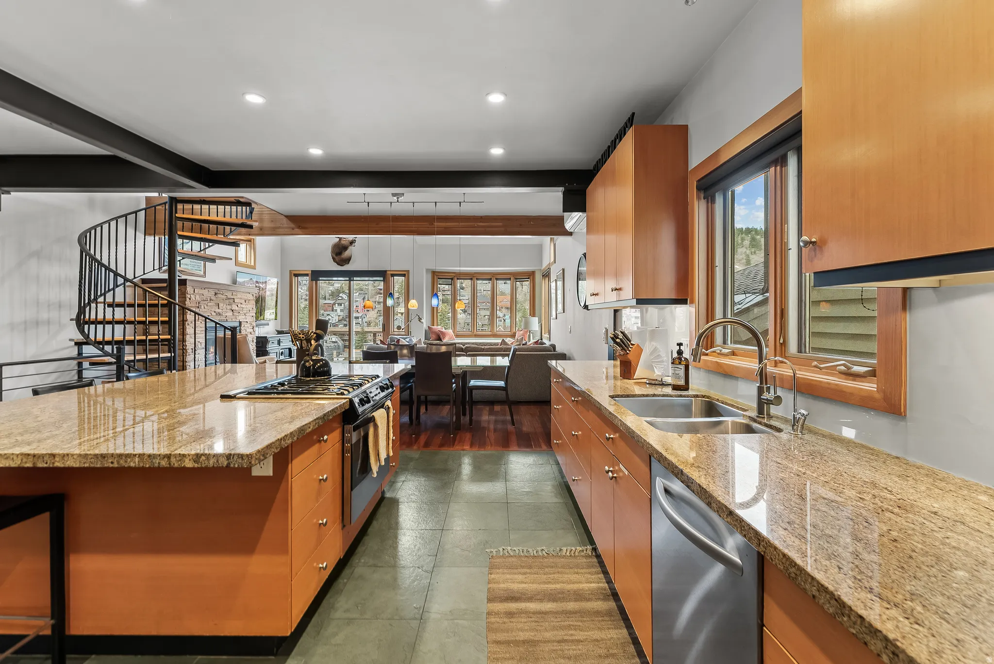 Kitchen with light stone counters, stainless steel appliances, wood finish cabinets, recessed lighting, and a kitchen bar