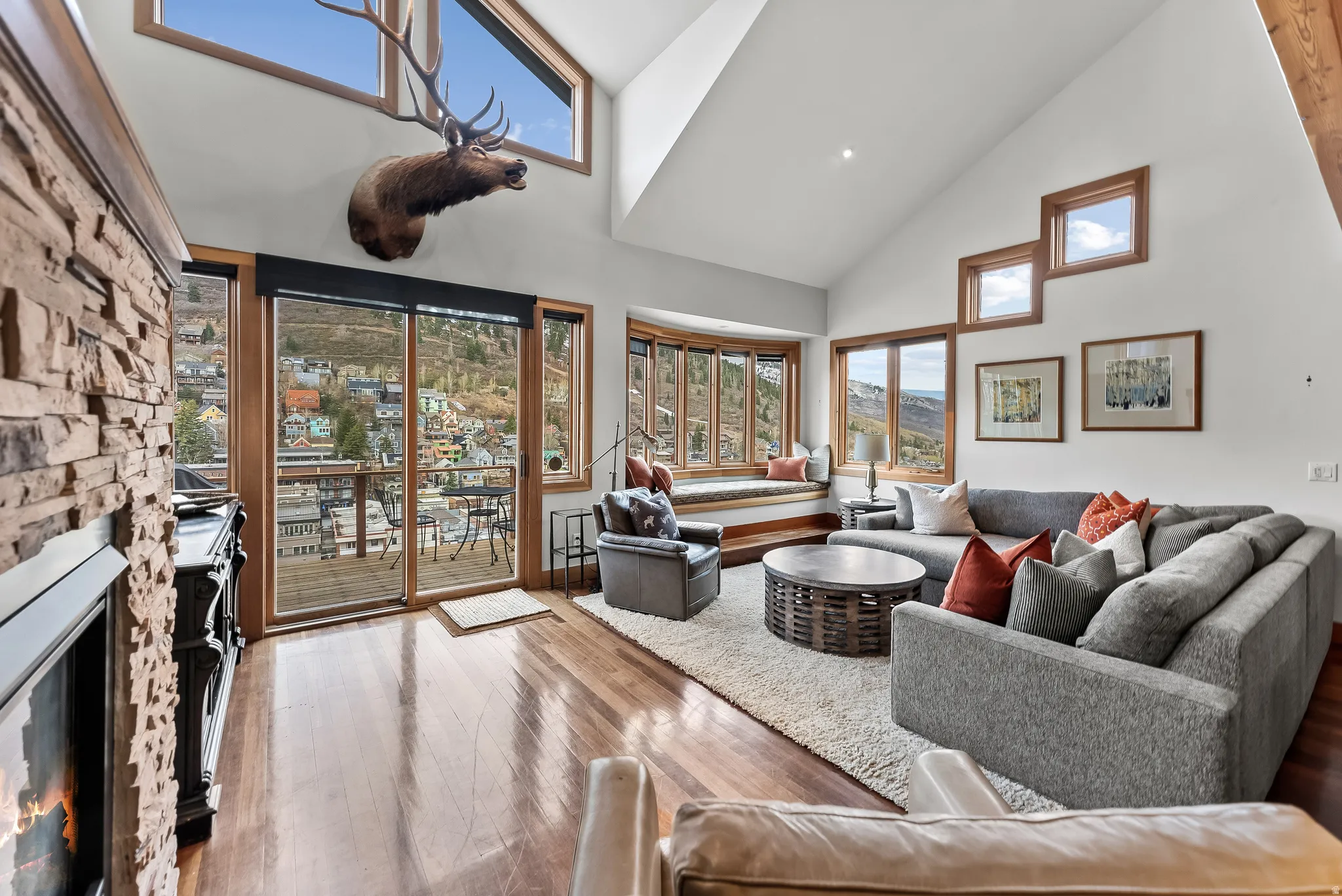 Living room with a stone fireplace, hardwood / wood-style flooring, and lofted ceiling