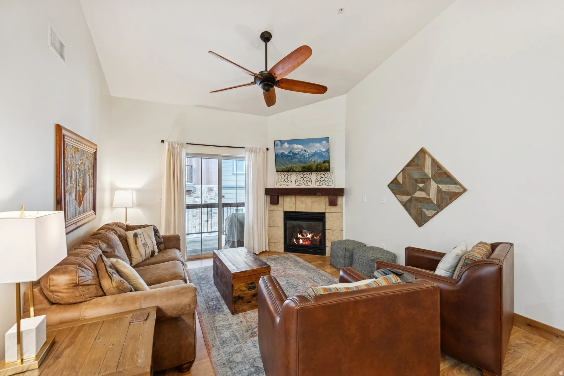 Living room featuring wood finished floors, a fireplace, and ceiling fan