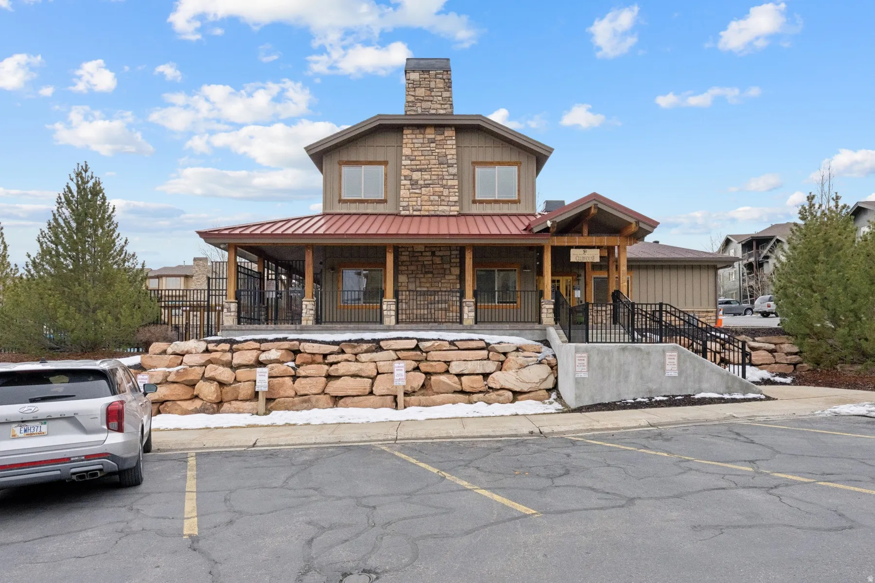 View of front of house featuring uncovered parking, covered porch, a chimney, a metal roof, and stone siding