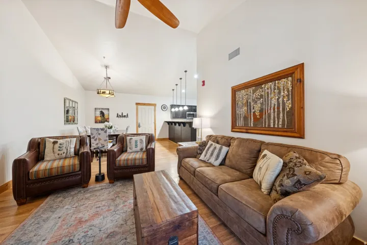 Living area with a ceiling fan, lofted ceiling, and light wood-style flooring