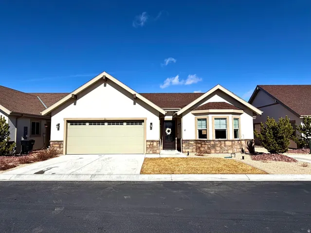 View of front of house featuring stone siding, stucco siding, driveway, an attached garage, and roof with shingles