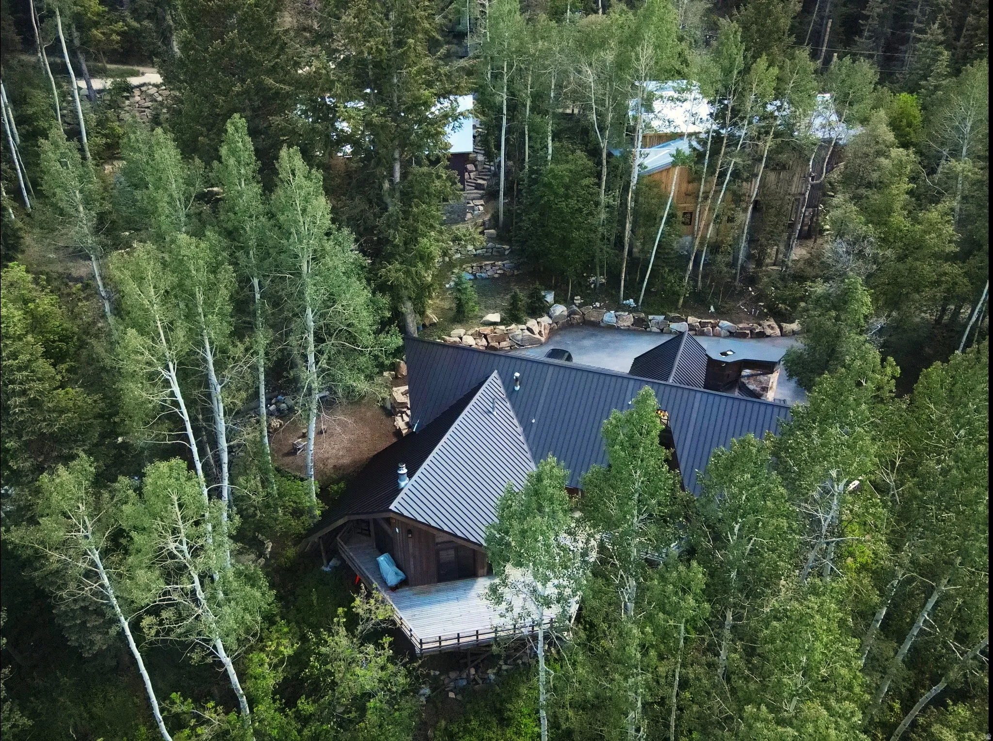Wood-sided residence featuring a dark metal roof and an expansive exterior deck