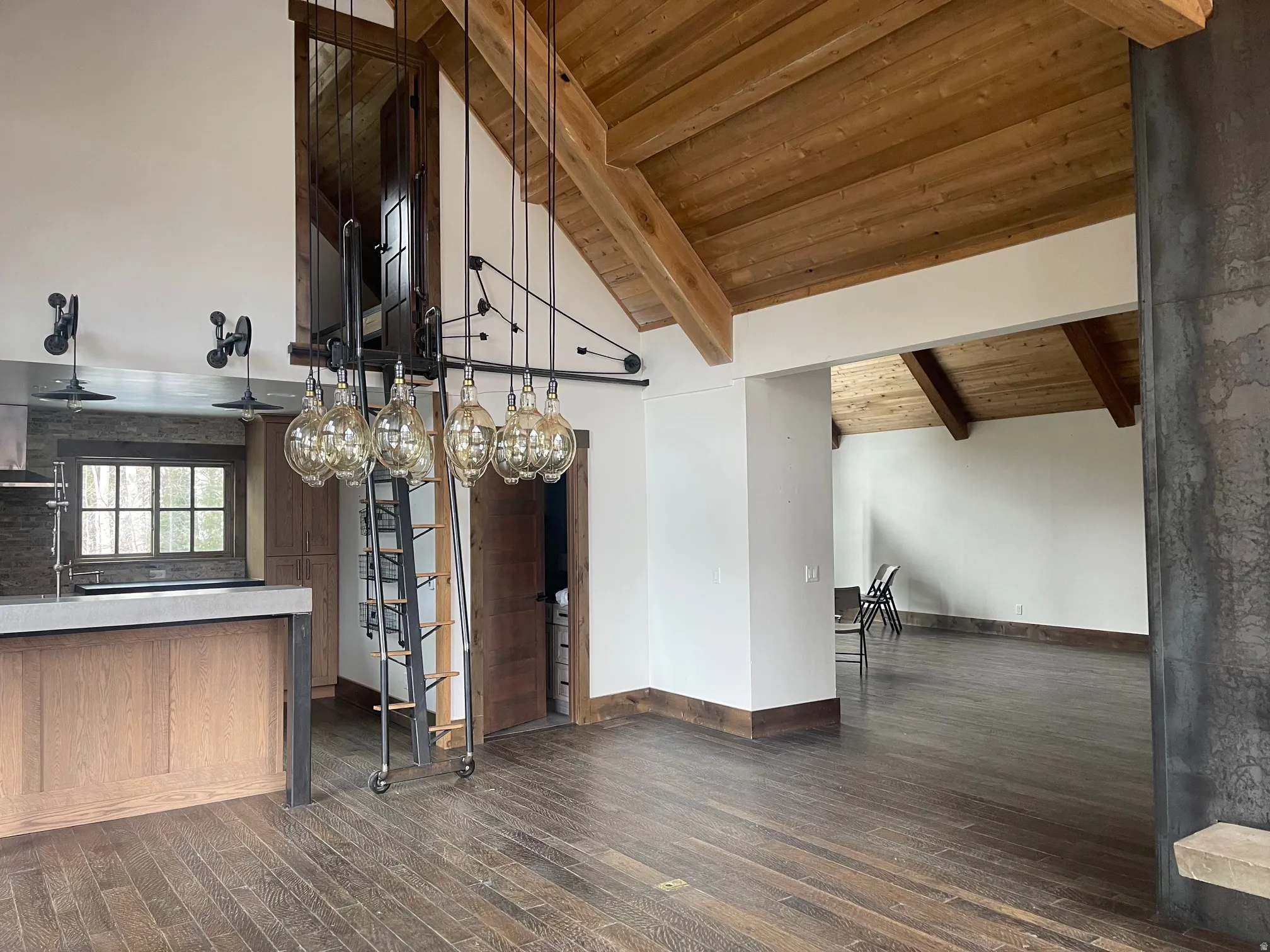 Unfurnished dining area featuring a high wood beamed ceiling, dark wood-style floors, and wet bar
